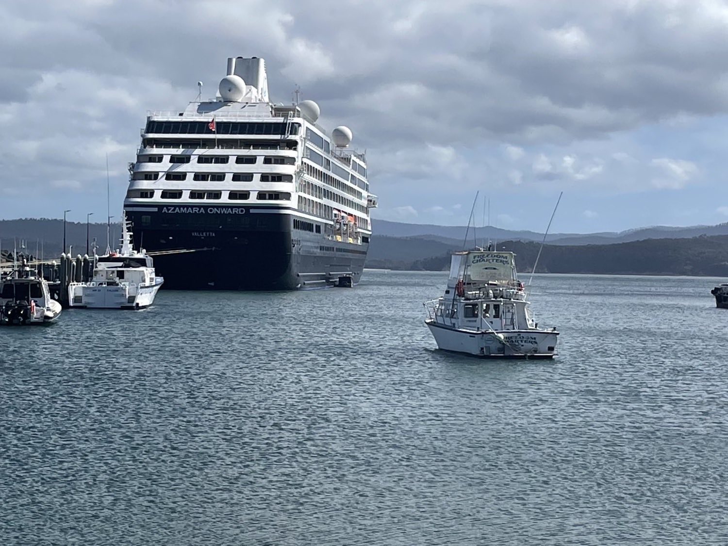 A cruise ship berthed at the Eden wharf with charter boats alongside