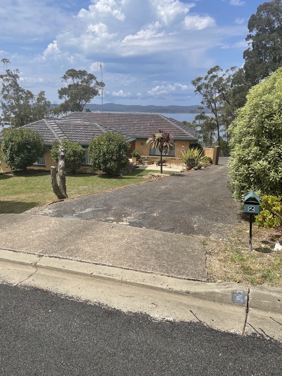 A brick home with a long driveway and water views over the bay